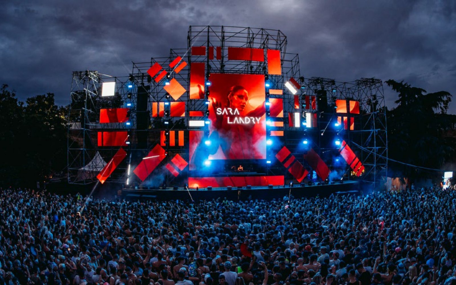 A large crowd at dusk in front of a red LED stage at an earlier EXIT Festival edition.
